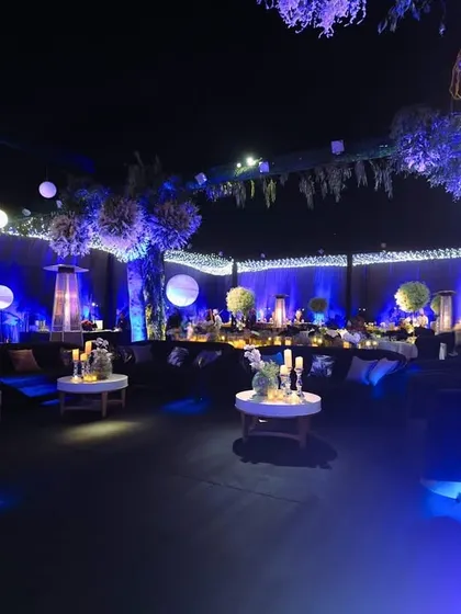 A wide view of the dreamy lounge setup, with neon-lit trees, hanging globe lights, and cozy seating areas creating a magical, ethereal environment.