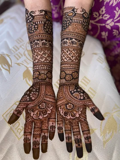 A gorgeous full-arm design featuring peacocks at the top, surrounded by intricate floral and geometric patterns.