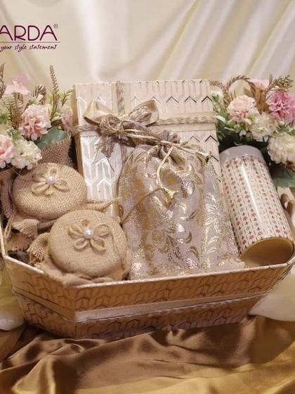 A beautifully curated gift basket featuring a variety of textures and items. It includes decorative boxes, burlap pouches, and floral arrangements, creating a shabby-chic aesthetic perfect for bridal room hampers.
