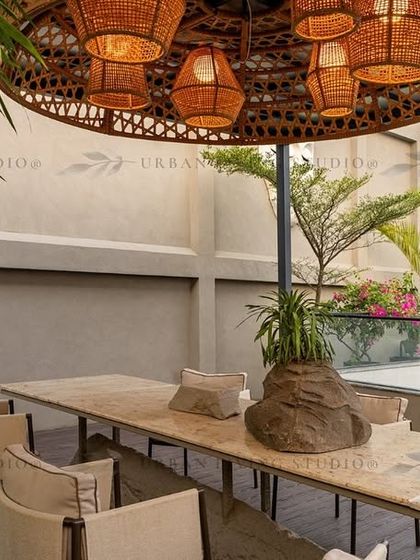 This outdoor dining area in Aligarh is perfect for hosting. The centerpiece is a long marble table under a stunning oversized wicker chandelier, surrounded by lush bamboo for privacy.