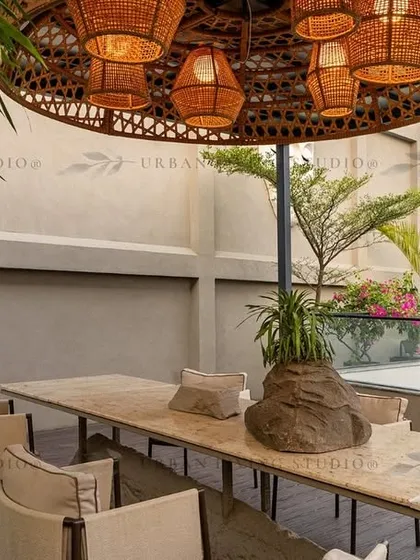 This outdoor dining area in Aligarh is perfect for hosting. The centerpiece is a long marble table under a stunning oversized wicker chandelier, surrounded by lush bamboo for privacy.