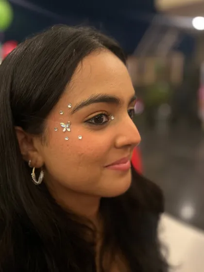 A tiny flower made of rhinestones surrounded by a sprinkle of more gems. It's a sweet and delicate design that's perfect for any occasion.