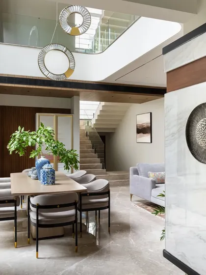 A view from the hallway into the open-plan dining and living area. The design allows for easy flow between spaces, making it ideal for entertaining, while distinct material and lighting choices define each zone.