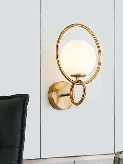 A beautiful ring-shaped designer wall lamp in antique brass. The glowing white globe is encircled by a golden ring, creating a piece that is both a light fixture and a piece of modern jewelry for your wall.