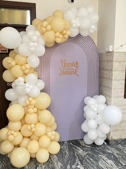 A closer view of the 'Umrah Mubarak' backdrop, showing the elegant script and the pastel balloon arrangement.