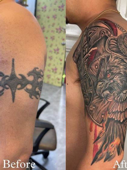 A fantastic before-and-after of a shoulder cover-up. The old tribal band is completely gone, replaced by a fierce warrior owl design with bold red accents. This is a total transformation.