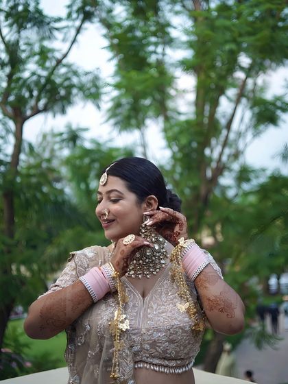 A bride adjusts her large, ornate earring, a classic getting-ready shot.