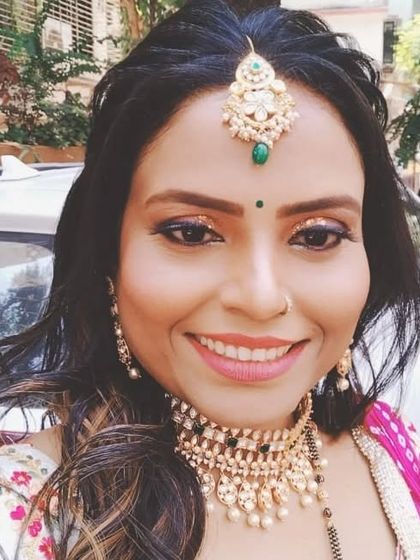 A happy client ready for a wedding celebration. She is wearing a Kundan choker with a matching maang tikka, looking festive and bright.