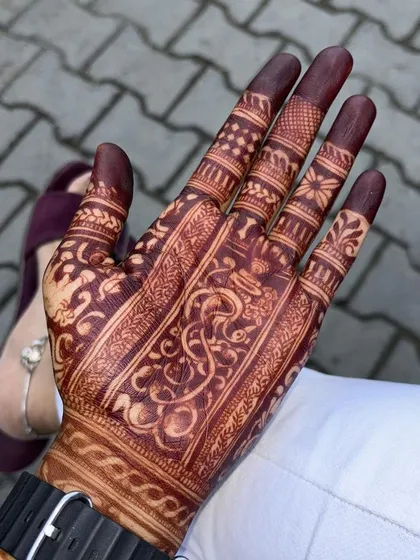 A groom's mehndi, showing the rich, dark stain on his palm. The design is a traditional pattern, perfect for wedding ceremonies.