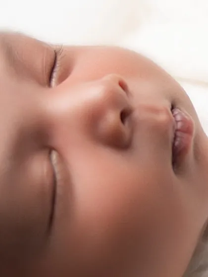 An intimate close-up of a newborn's face, highlighting their soft skin, delicate eyelashes, and tiny pursed lips. These detail-oriented shots preserve the memory of how small they truly were.