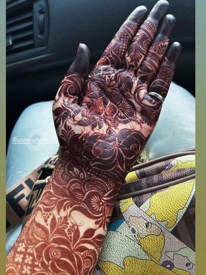 A close up of the rich, dark stain on the wrist and hand. The floral and leafy patterns are clearly defined, showcasing the quality of the henna art.