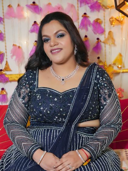 A smiling portrait showing off the dramatic blue eye makeup. It's a fun and festive look for someone who loves to make a statement.