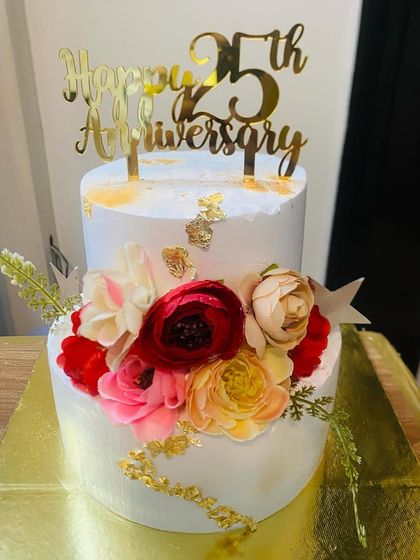 A stunning 25th-anniversary cake adorned with a cascade of artificial flowers.