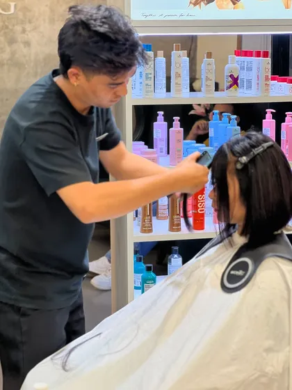 A stylist carefully cutting bangs, with our professional product display in the background.