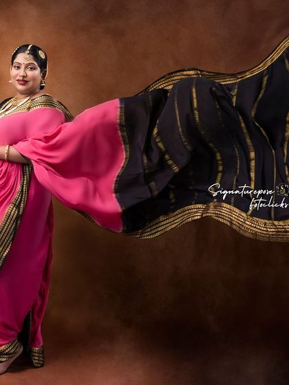 The dramatic flow of the pink and black saree creates a powerful and artistic statement in this portrait.