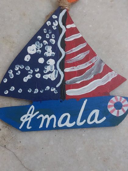 A personalized wooden boat nameplate, painted with patriotic colors. These custom crafts are a popular choice in our workshops.