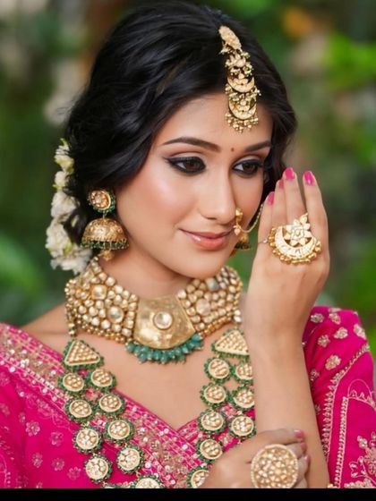 A close-up of the jewellery paired with our rani pink lehenga. This multi-layered kundan set with green beads is a royal choice for any bride.