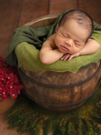 Meet Anshu, a six-day-new cherub resting in a wooden bucket. The rich green and red tones create a beautiful, earthy feel for this newborn portrait.