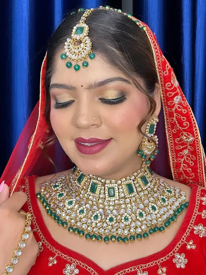 A close-up of a stunning bridal look with green jewelry and golden eyeshadow, taught in a professional batch.