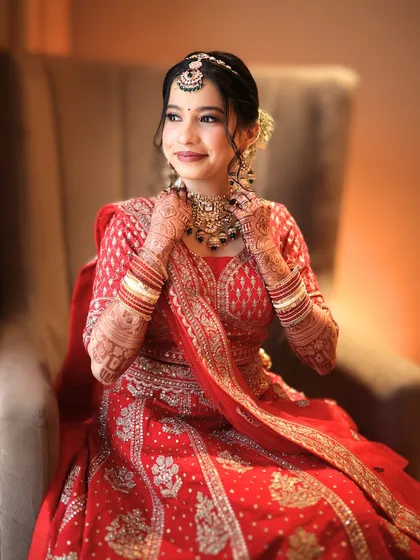 A seated portrait that exudes elegance. The bride's smile and the soft lighting create a warm and inviting image, showcasing her complete bridal look.
