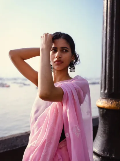 Shot at the Gateway of India, with the sea and boats in the background. The natural light and pose create a soft, breezy feel.