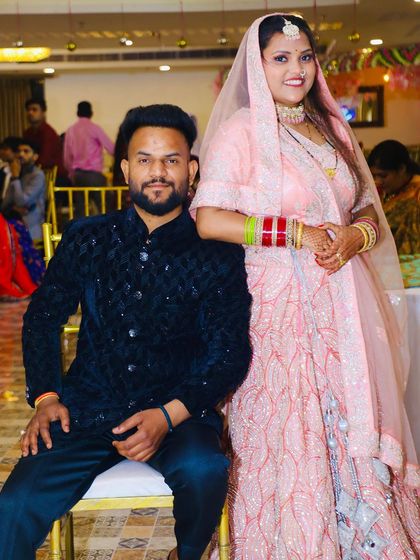 A happy couple at their event. The bride is wearing our light pink embroidered lehenga, showing how our outfits look in a real-life celebration.