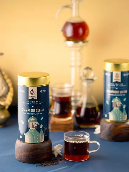 A sophisticated shot of Hindraj's Champagne Sultan black tea. The deep blue background and elegant glassware give this image a premium, almost majestic feel, perfect for a luxury tea brand.