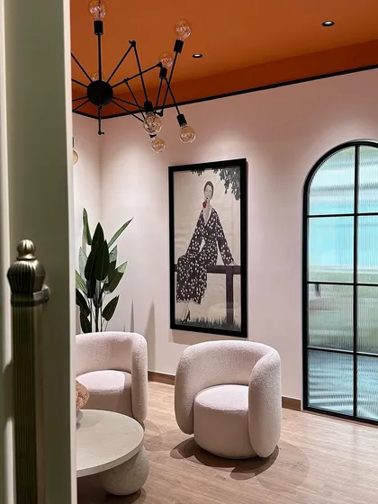 The lighting and architectural details are key to setting a mood. Here you can see the modern, multi-bulb chandelier and the bold orange ceiling, which create a dramatic and warm effect in the lounge area.