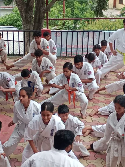 A young student smiles during a stretching exercise. Even during a tough grading, the joy of learning and pushing one's limits shines through.