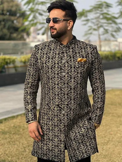 A close-up of the black and gold brocade Indo-Western, highlighting the intricate pattern and the luxurious texture of the fabric.