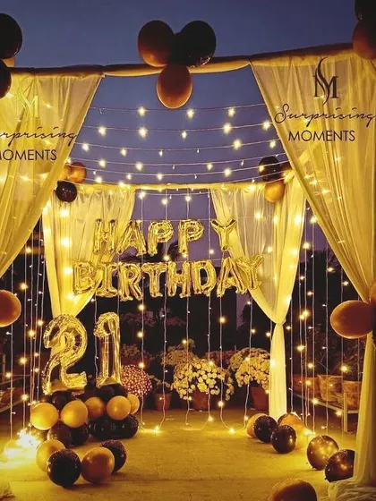 A stunning terrace transformation for a 21st birthday. I created a canopy with drapes and fairy lights, adding 'Happy Birthday' foil balloons and light-up numbers for a perfect outdoor party ambiance.