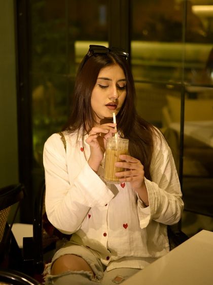 A solo coffee date look. A casual white shirt with red hearts, paired with ripped jeans.