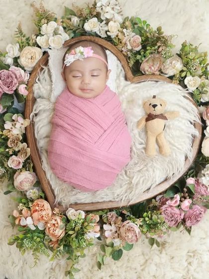 An overhead view of the heart-shaped floral basket, showcasing the beautiful arrangement of flowers and the peacefully sleeping baby.