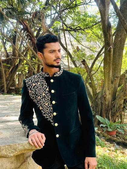 A profile shot in an elegant, embroidered jacket, showcasing the detailed craftsmanship on the shoulder and sleeve.