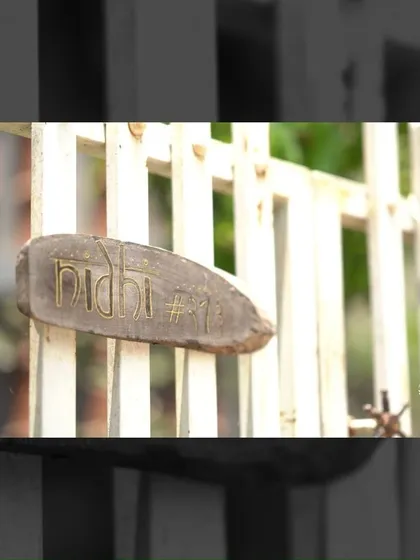 Duplicate of 138. The home's name, 'Nidhi', is carved into a rustic piece of wood at the entrance gate, offering a personal and handcrafted welcome.