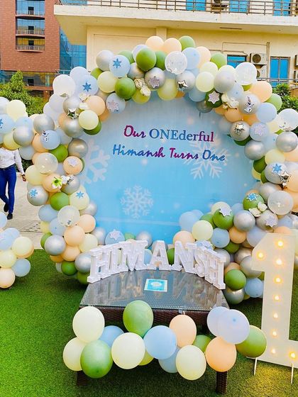 A 'ONEderful' first birthday party with a cool, winter-themed pastel color palette. The setup includes a circular backdrop, a full balloon arch, and light-up name and number props.