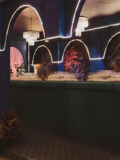 The bar is a key social hub, and I make sure it's a statement piece. This bar features a custom arched structure with integrated chandeliers and dramatic backlighting to match the contemporary theme.