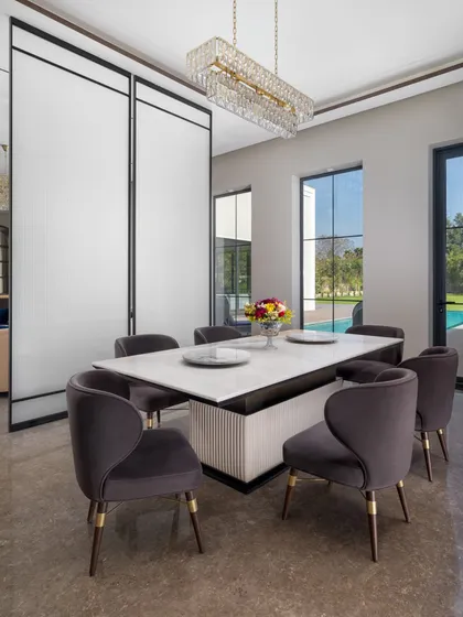 Another view of the dining room, showing its connection to the outdoors with large windows looking out onto the pool and garden. The plush velvet chairs invite long, comfortable meals with family and friends.