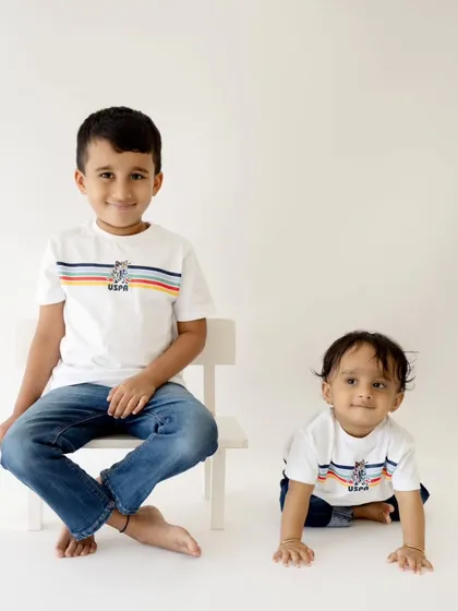 A fun and creative portrait of two brothers. The older brother sits on a chair while the younger one crawls nearby, capturing their different stages and personalities.