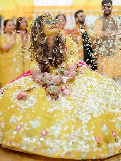 A beautiful portrait of the bride, looking up with a joyful expression as she is covered in a sea of white and yellow flowers.