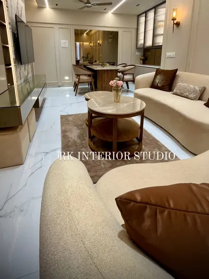 An overhead view of a modern living room I designed. The curved sofa, tiered center table, and soft rug create a comfortable and sophisticated seating area, complemented by the elegant dining space in the background.