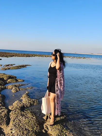 Standing by the serene waters in Dwarka. A flowy shrug over a black dress is a versatile beach look, perfect for exploring the coastline.