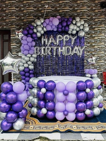 A full view of the purple and silver birthday decoration, including a decorated cake table.