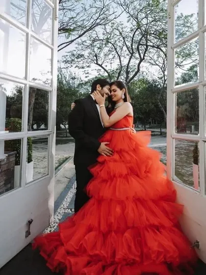 The voluminous skirt of our red ruffled gown fills the doorway in this stunning pre-wedding shot, creating a sense of grandeur and romance.