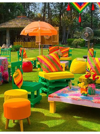 Bright and colorful seating arrangements for a Holi party, using painted pallets and vibrant cushions. This shows how I create functional and thematic lounge areas for large outdoor gatherings.