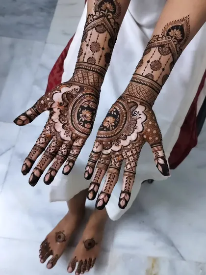 This elegant design features a central lotus mandala, with matching patterns extending up the wrist. The hint of feet mehendi shows how you can coordinate your whole look.