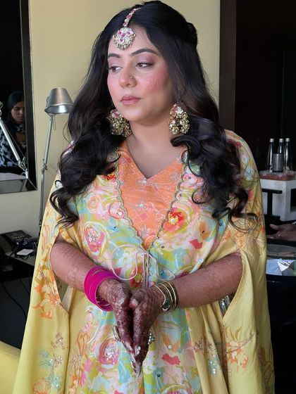 A client with a fun and colorful half-up style with soft waves for her Mehendi.