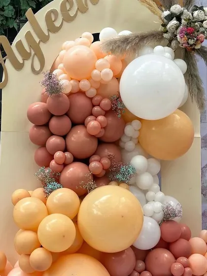 A detailed look at the custom gold 'Ayleen' name sign and the rich texture of the balloon garland.