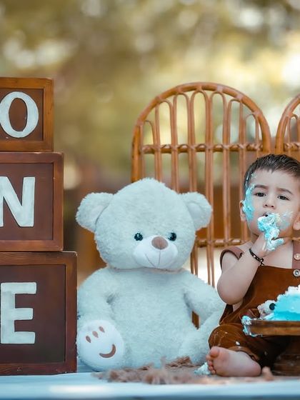 The first taste of birthday cake, surrounded by nature. This outdoor setup combines rustic props like wooden 'ONE' blocks with the simple beauty of the park.