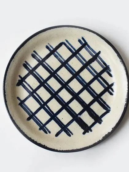 A rustic, cream-colored plate with a bold, hand-painted blue hashtag pattern. This piece is part of our eclectic collection that adds a playful touch to your tableware.